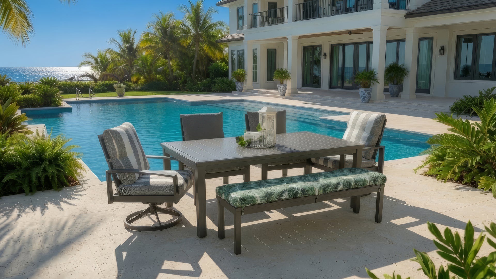 Outdoor seating set shown on residential rear patio with large square stone pavers. Outdoor seating set contains cushioned aluminum sofa with four toss pillows, cushioned club chair with toss pillow, square end table and rectangular cocktail table.