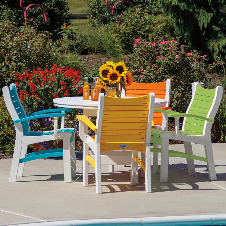 Outdoor poly timber dining set with four multi color dining arm chairs and round dining table in outdoor setting