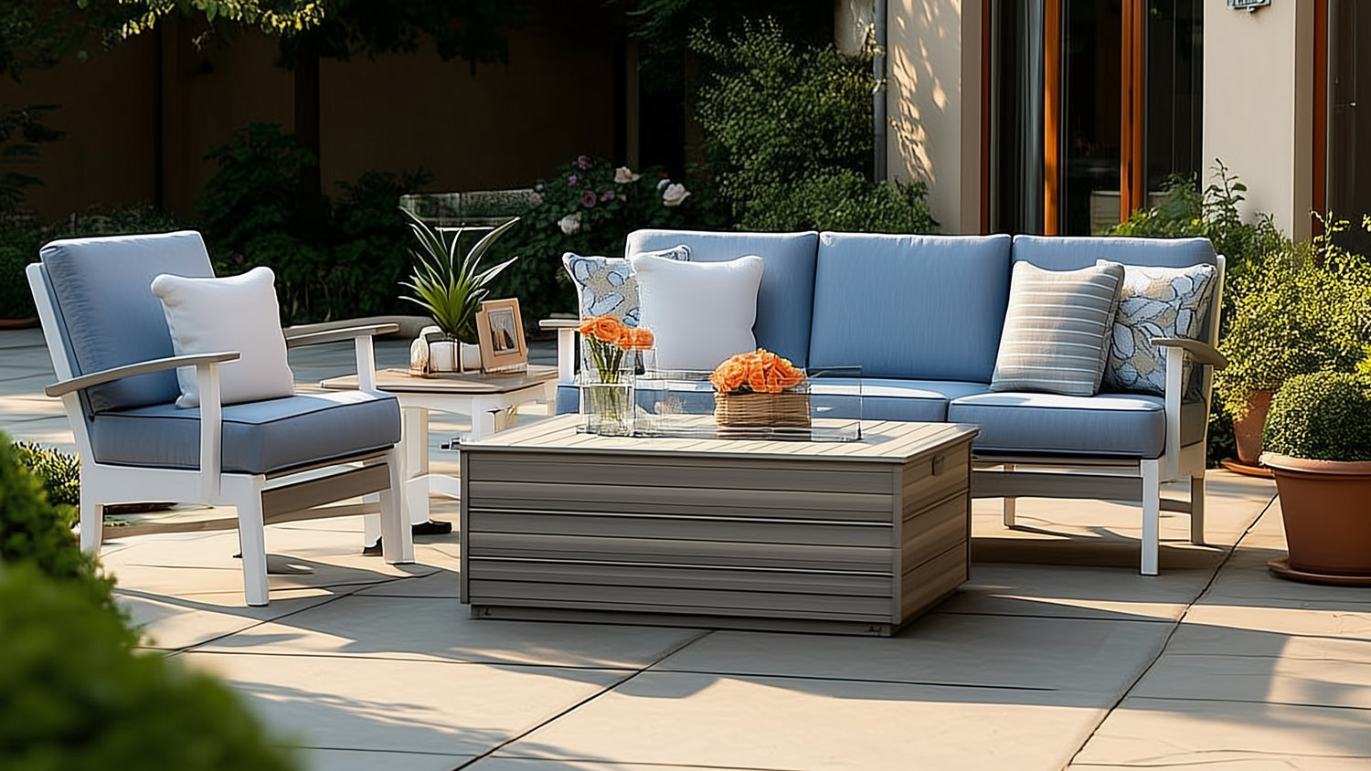 Outdoor poly timber cushioned seating set with sofa, club chair, end table and fire pit table on pavers in a backyard setting
