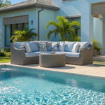 Outdoor wicker sectional with cushions and toss pillow in front of house by pool.